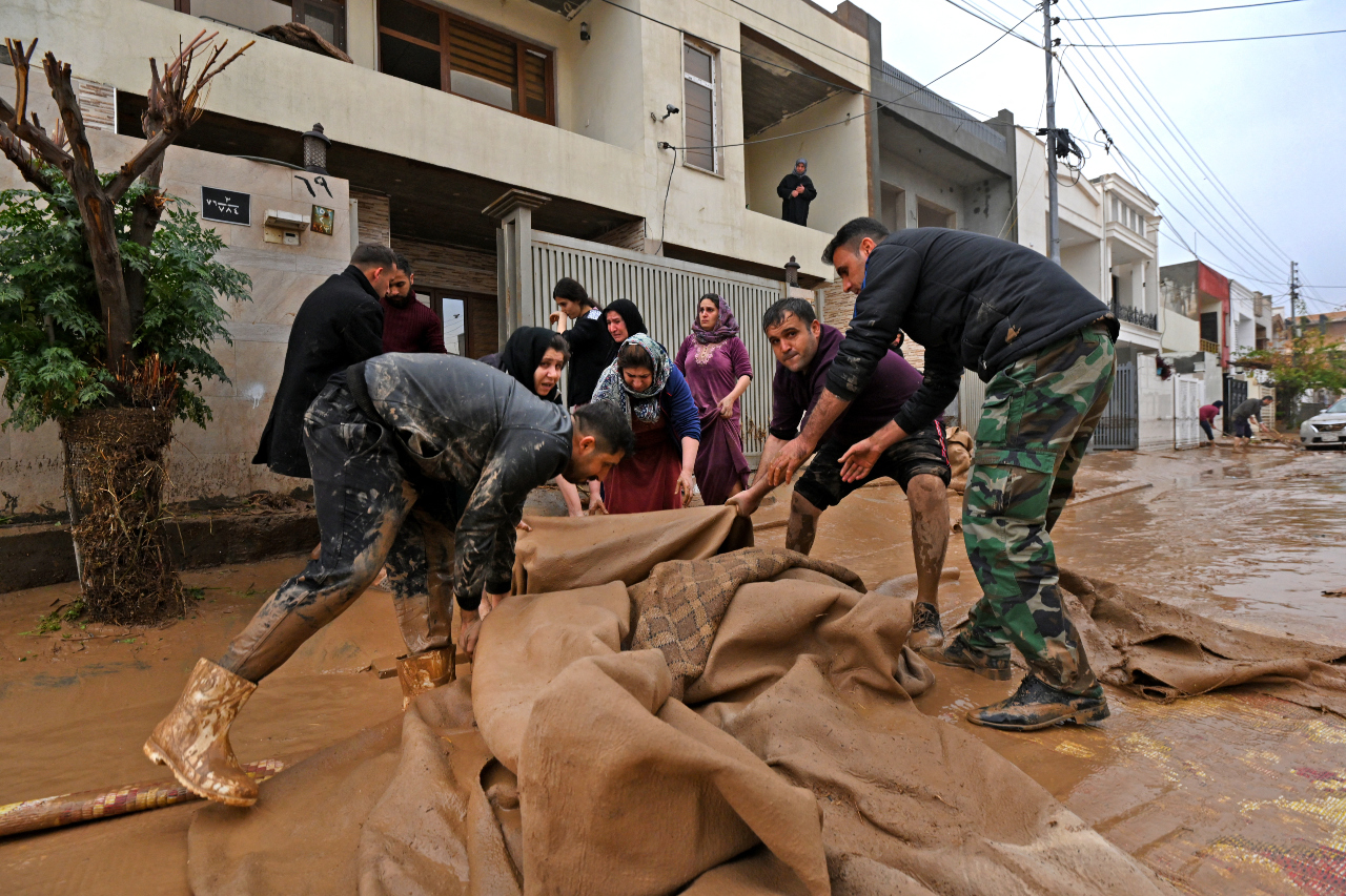 Residents clear debris in the area of Daratu, on the outskirts of Erbil (AFP)