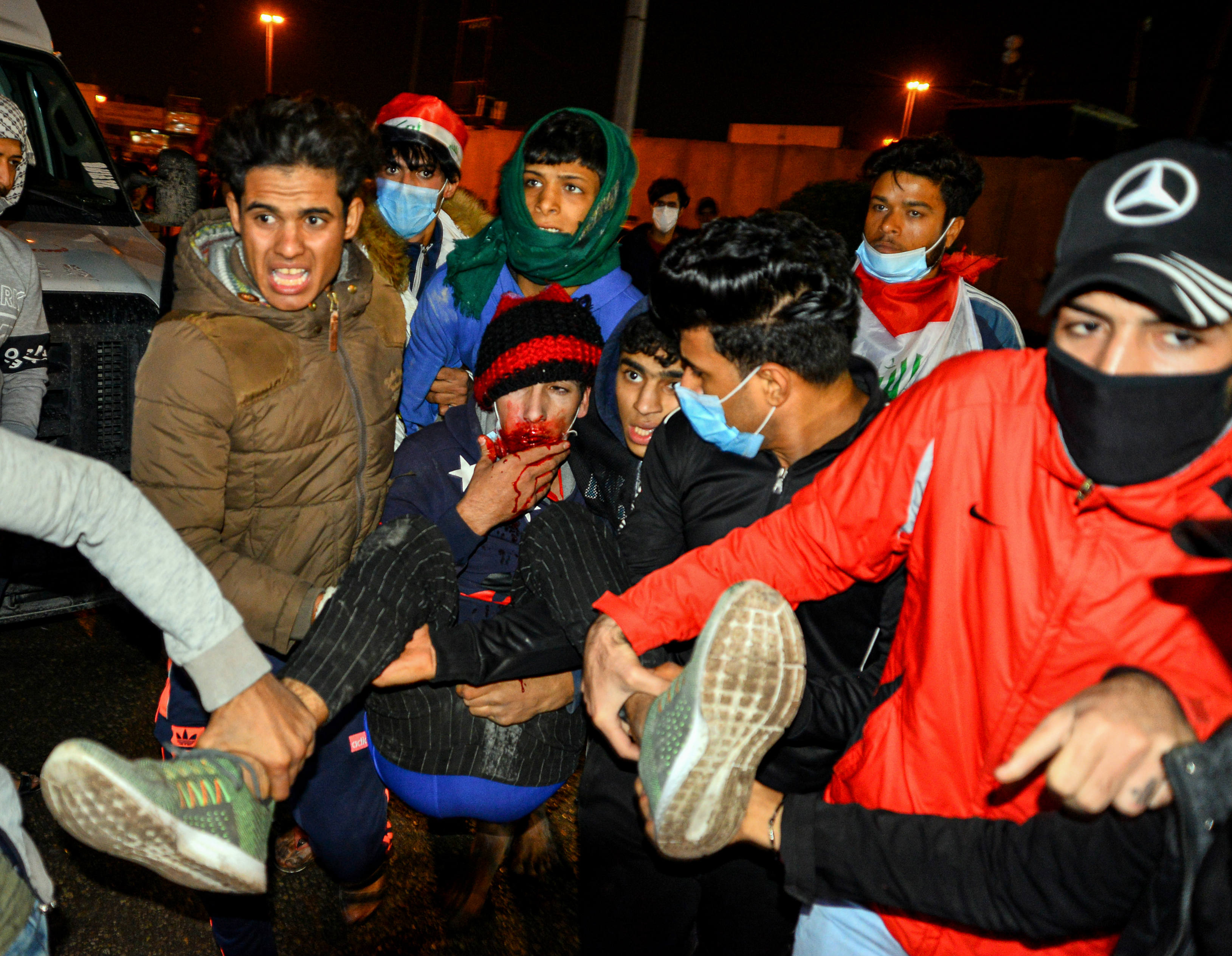 Des Irakiens transportent un manifestant -gouvernement blessé lors des affrontements avec les forces de sécurité à Nadjaf (AFP)