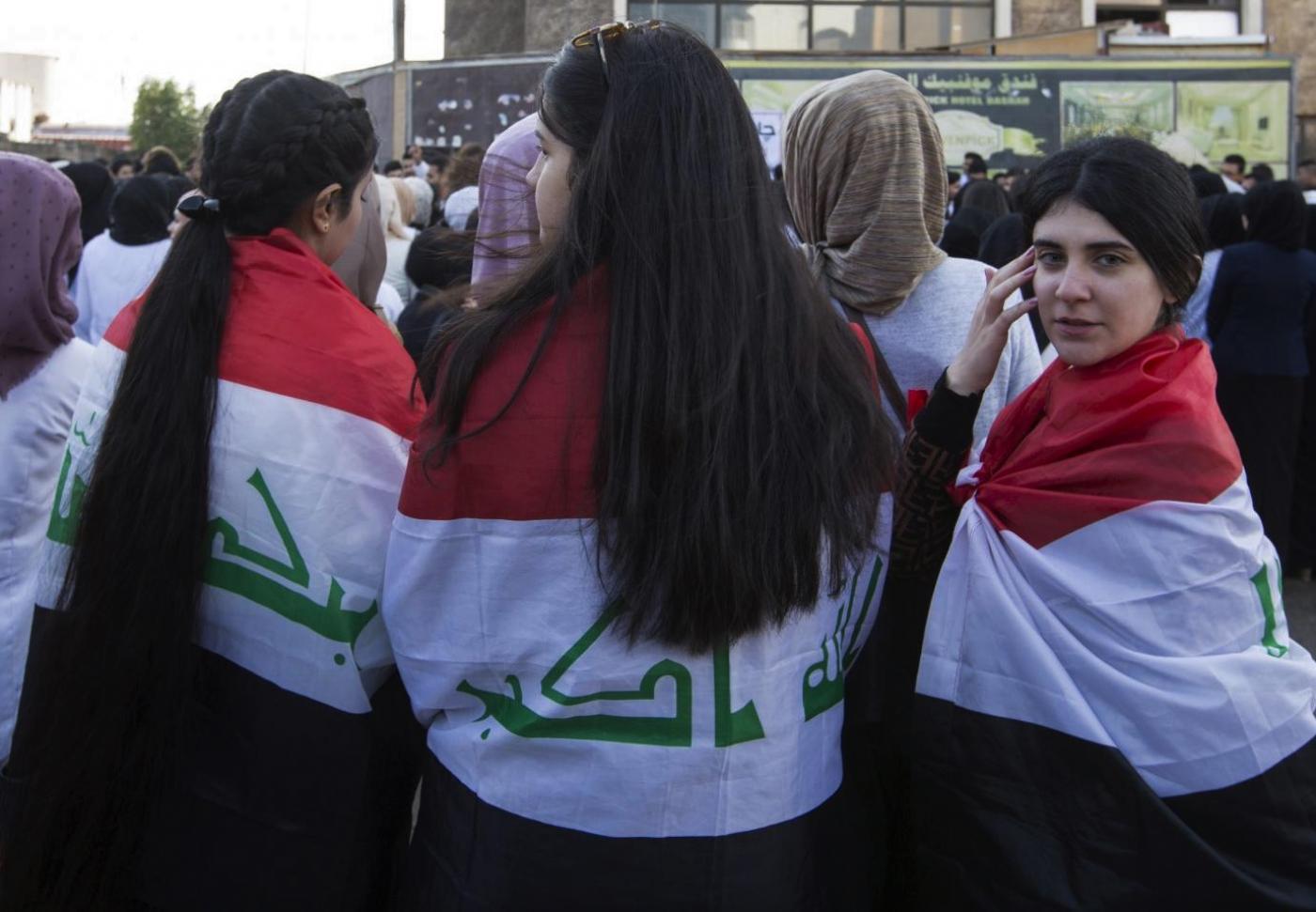 De jeunes Irakiennes enveloppées du drapeau national participent à une manifestation le 8 décembre 2019 (AFP)