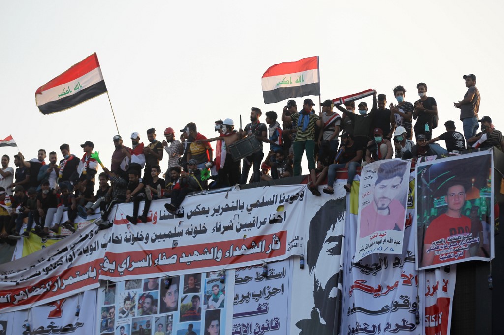 Des manifestants irakiens se tiennent au sommet d’un bâtiment abandonné à Bagdad le 31 octobre (AFP)