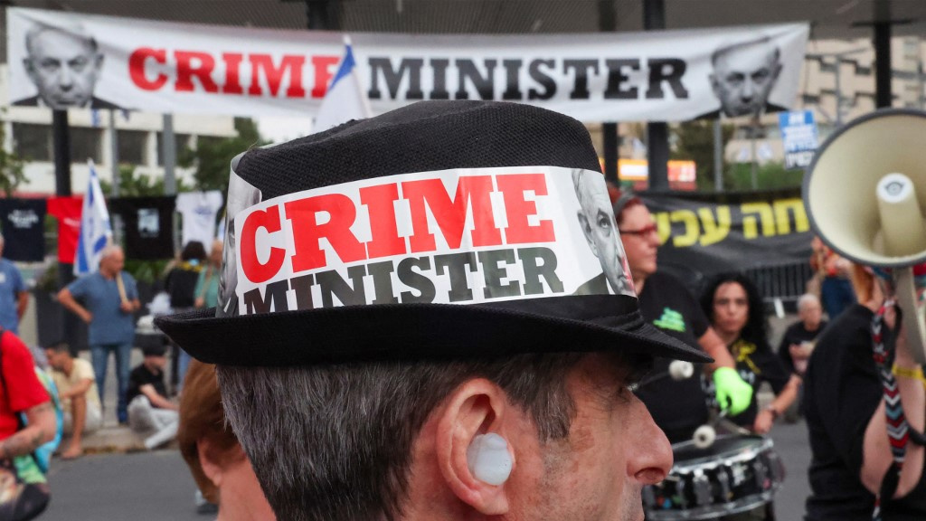 An Israeli protester wearing a hat with a slogan against Israeli Prime Minister Benjamin Netanyahu is pictured in Tel Aviv on 27 April 2024 (Jack Guez/AFP)