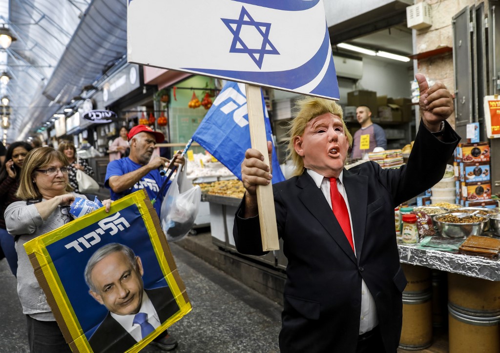 A supporter of Israeli Prime Minister Benjamin Netanyahu wears a mask portraying Trump’s face in Jerusalem on 7 April (AFP)