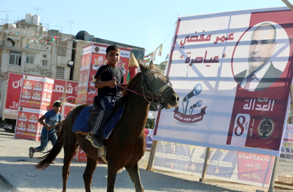 A boy rides a horse past election campaign posters in Amman in 2016 (AFP)
