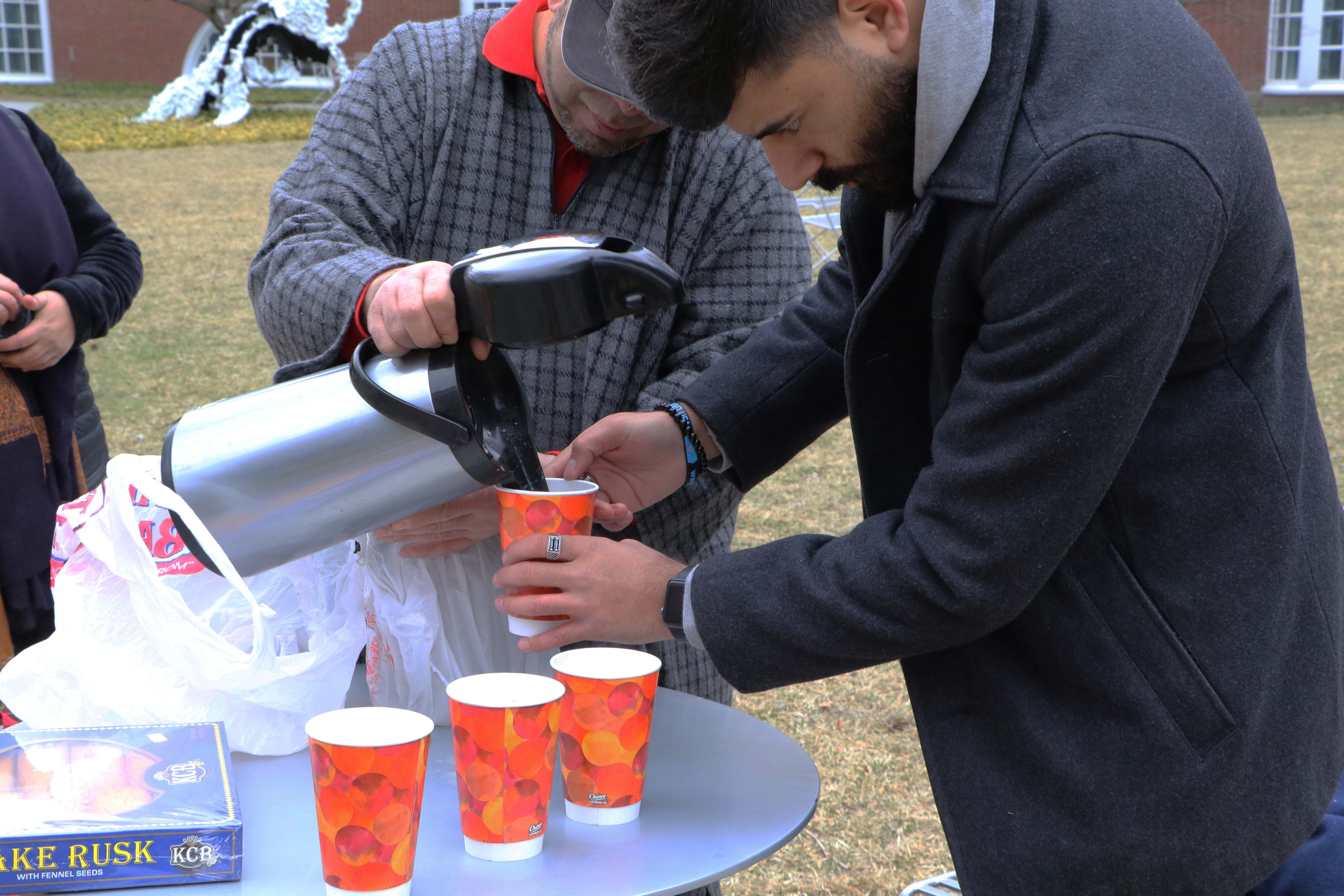 A man pours in tea into paper cups.