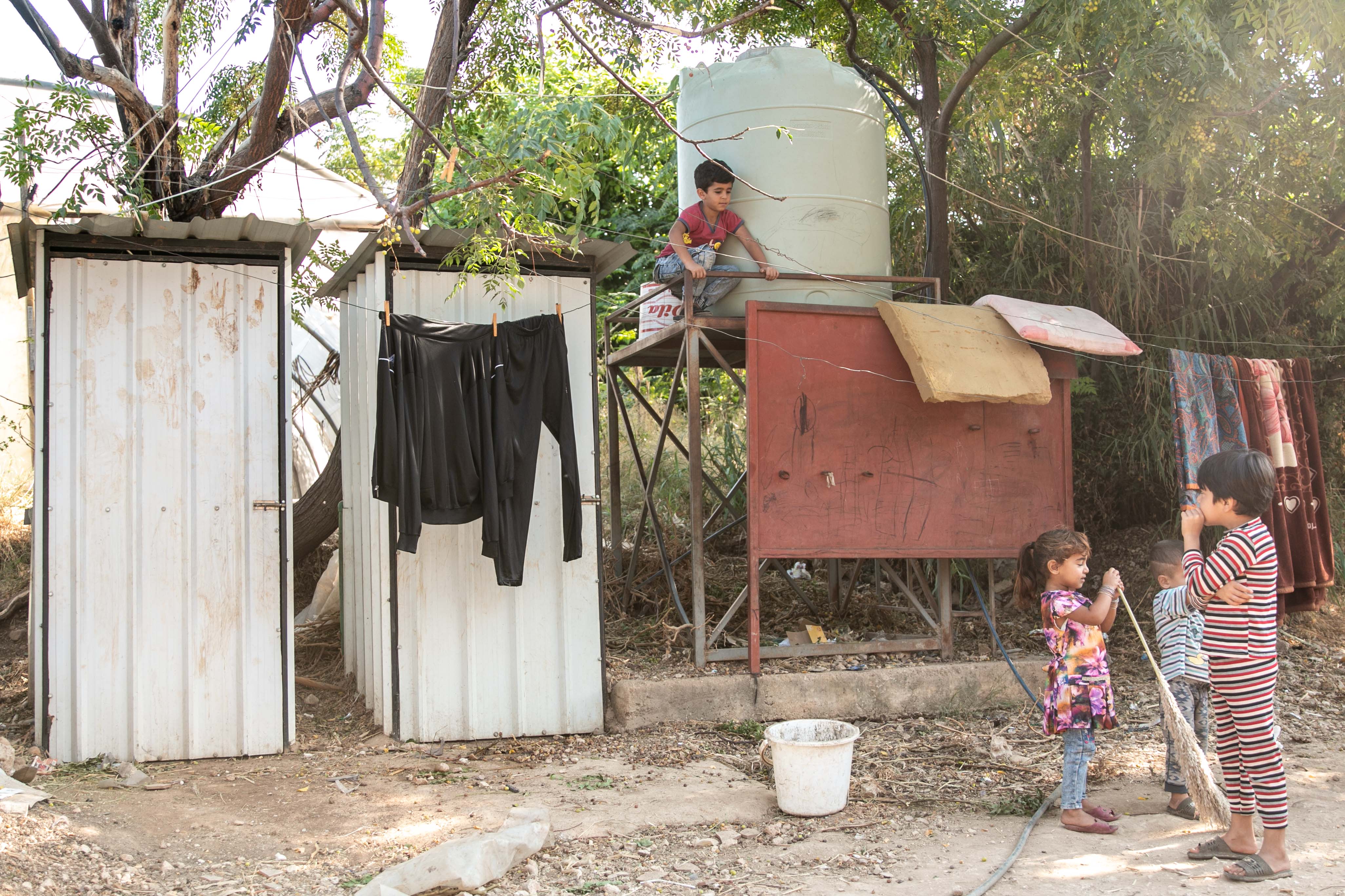 Des enfants jouent près des toilettes et citernes d’eau du camp 052 près de Bebnine – plusieurs ont contracté des maladies liées à l’eau (MEE/Philippe Pernot)