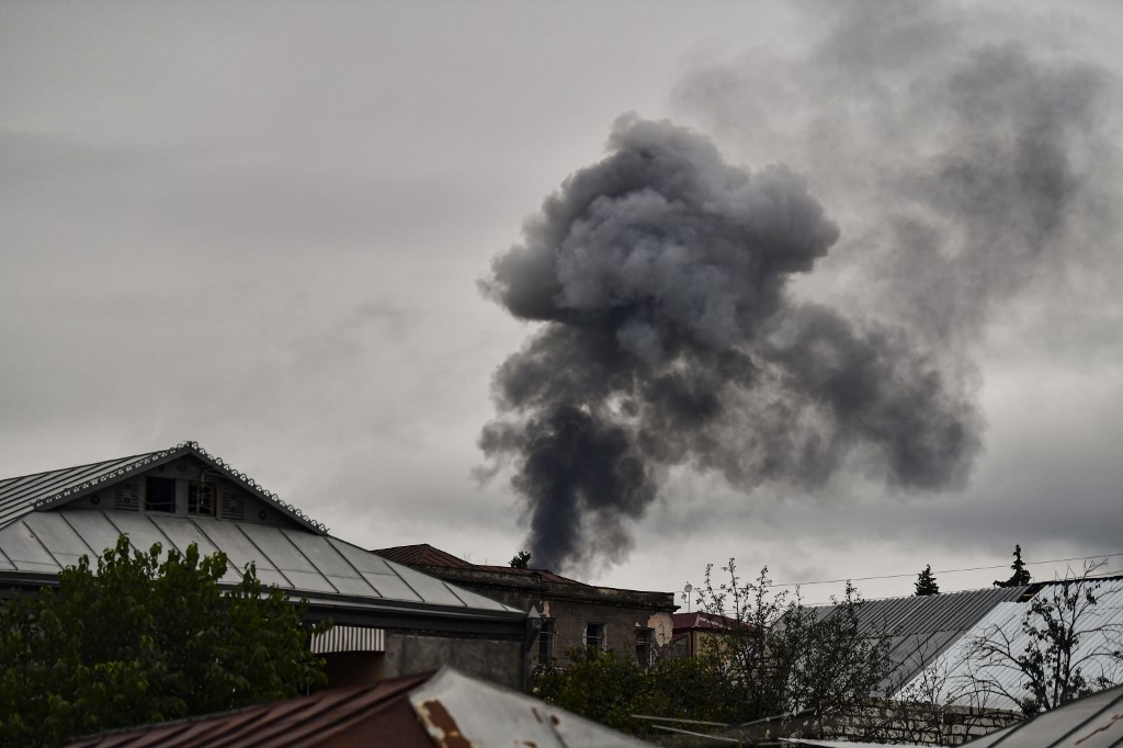 Smoke rises behind houses after shelling in Nagorno-Karabakh on 7 October (AFP)