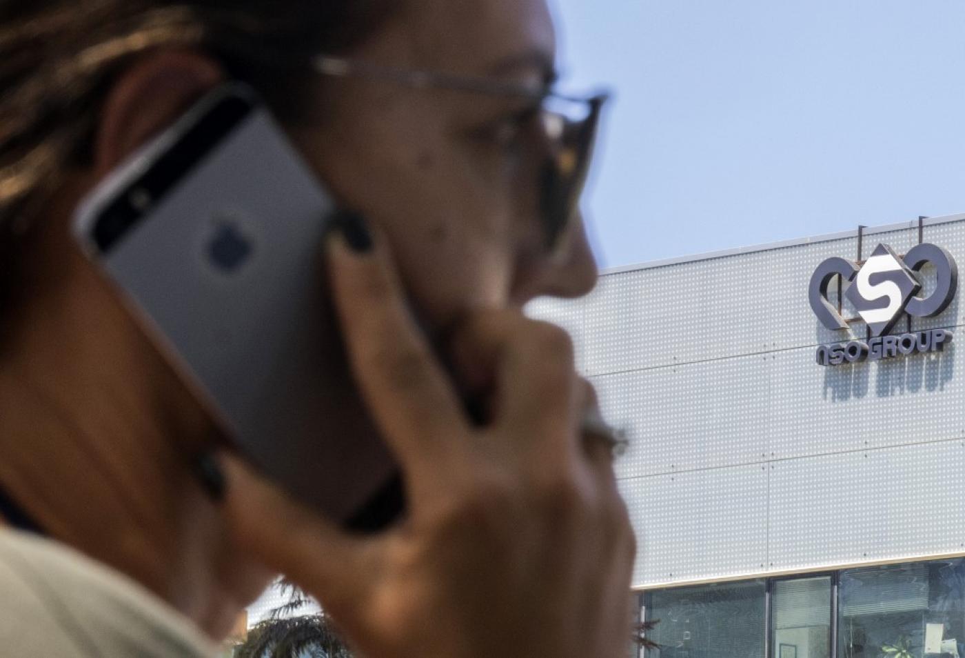 A woman uses her iPhone in front of the Israeli NSO group building in Herzliya in 2016 (AFP)