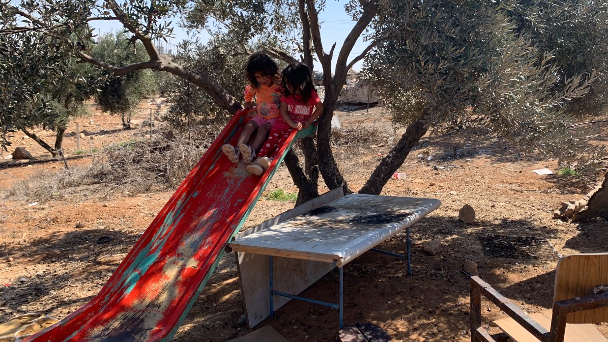 Two young Palestinian girls play on the broken slide in al-Asayfer (MEE/Shatha Hammad)