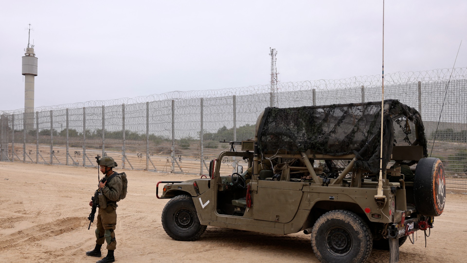 An Israeli soldier stands next to a vehicle parked by the fence along the border with the Gaza Strip near Moshav Netiv HaAsara in southern Israel on December 7, 2021