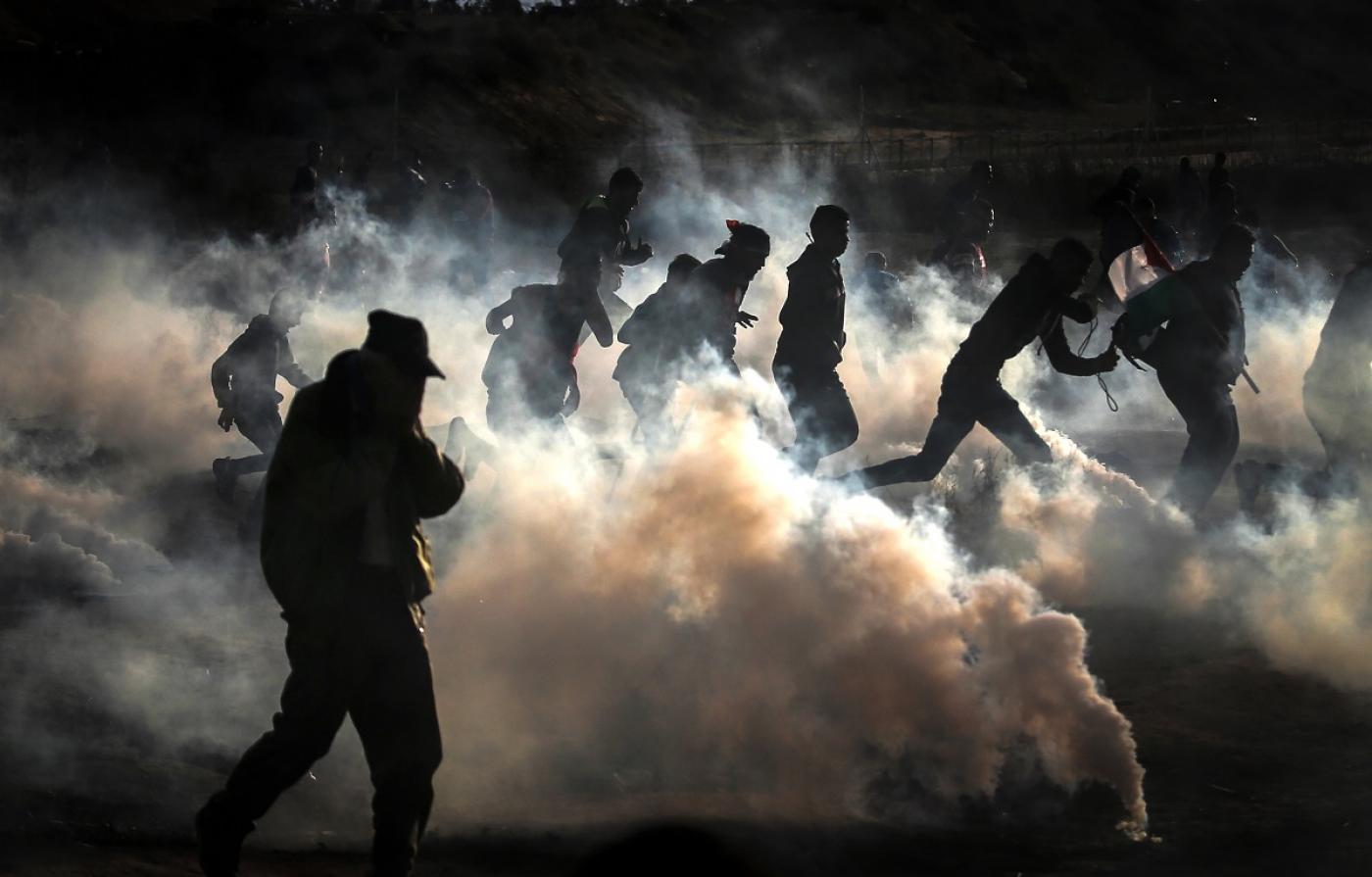 Des manifestants palestiniens fuient les tirs de gaz lacrymogène des forces israéliennes à l’est d’al-Bureij, dans le centre de la bande de Gaza, en décembre 2019 (AFP)