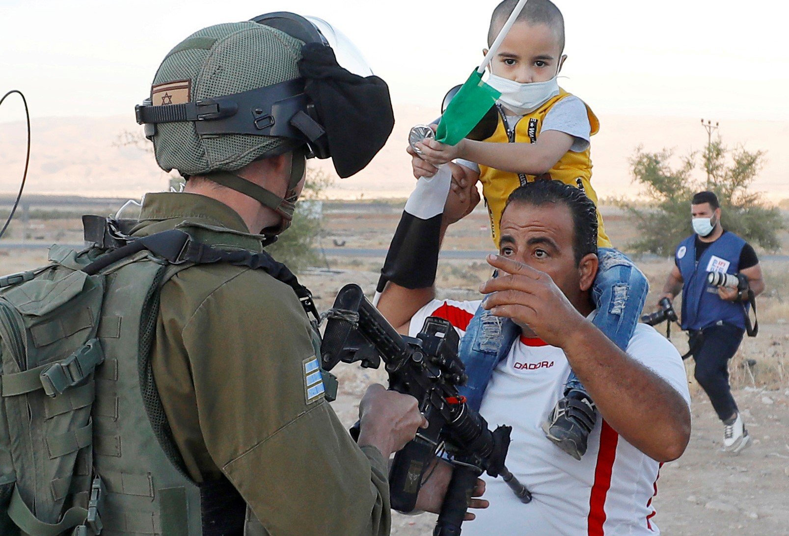 Un Palestinien avec son enfant face à un soldat israélien pendant une manifestation contre le projet d’Israël d’annexer des régions de Cisjordanie occupée, dans la vallée du Jourdain le 24 juin (Reuters)