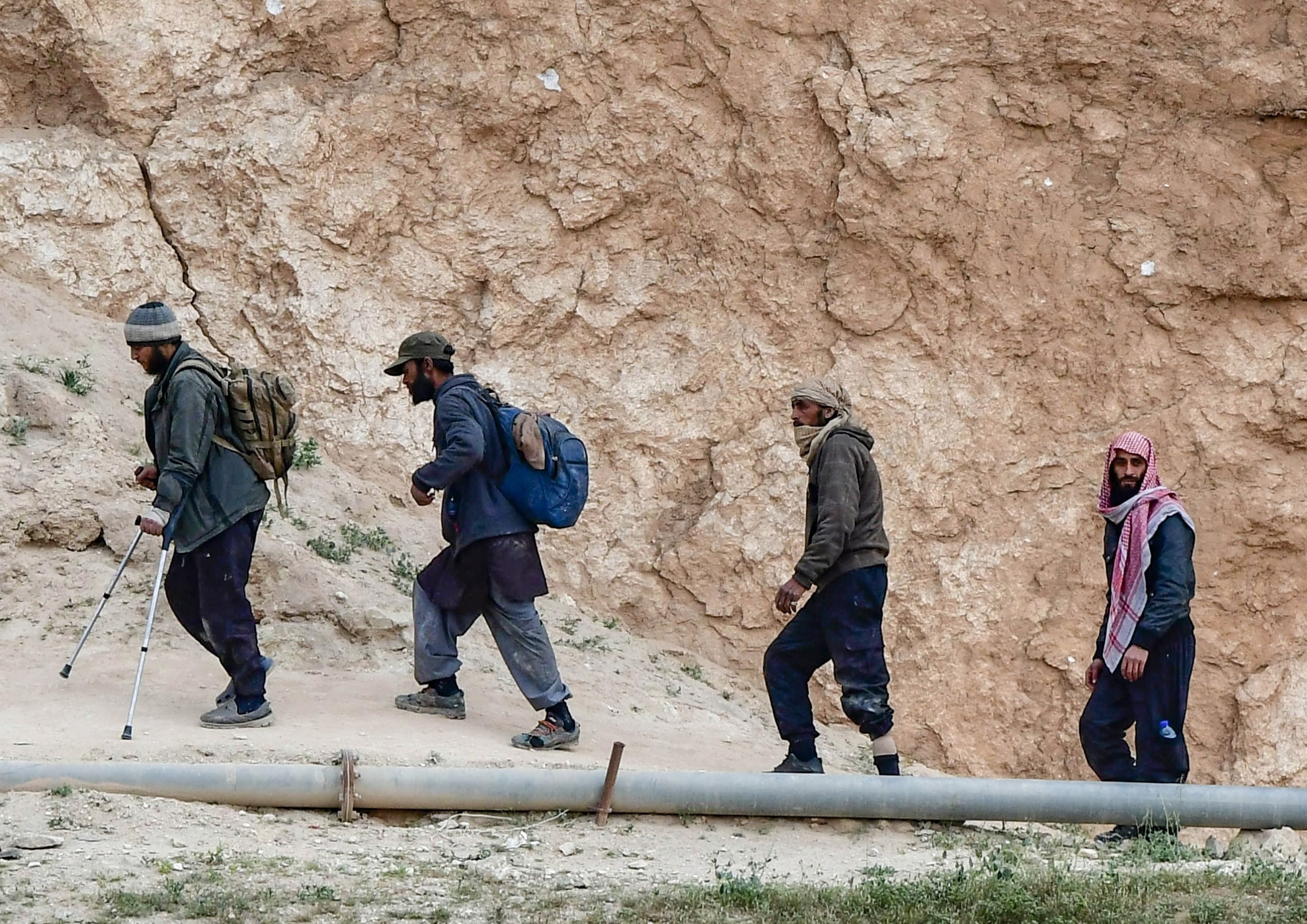 Des membres présumés de l'Etat islamique, sortent du village de Baghouz dans la province syrienne de Deir Ezzor (AFP)