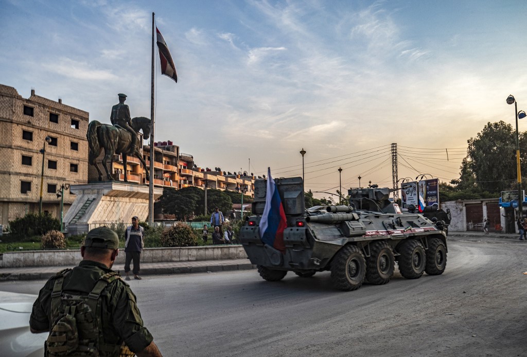 A Russian military vehicle drives in Qamishli, Syria, on 24 October (AFP)