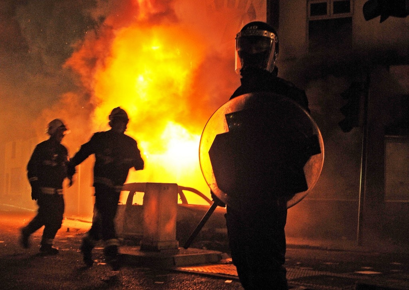 A riot police officer stands guard in front of a burning building during riots in Croydon, south London, in 2011 (AFP)
