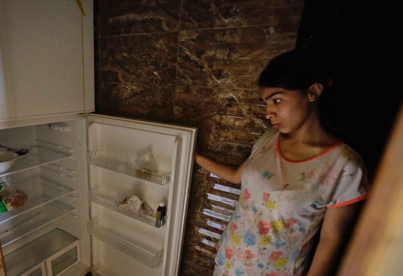 Une Libanaise regarde son réfrigérateur vide dans son appartement de Tripoli, au nord de Beyrouth, le 17 juin 2020 (AFP)
