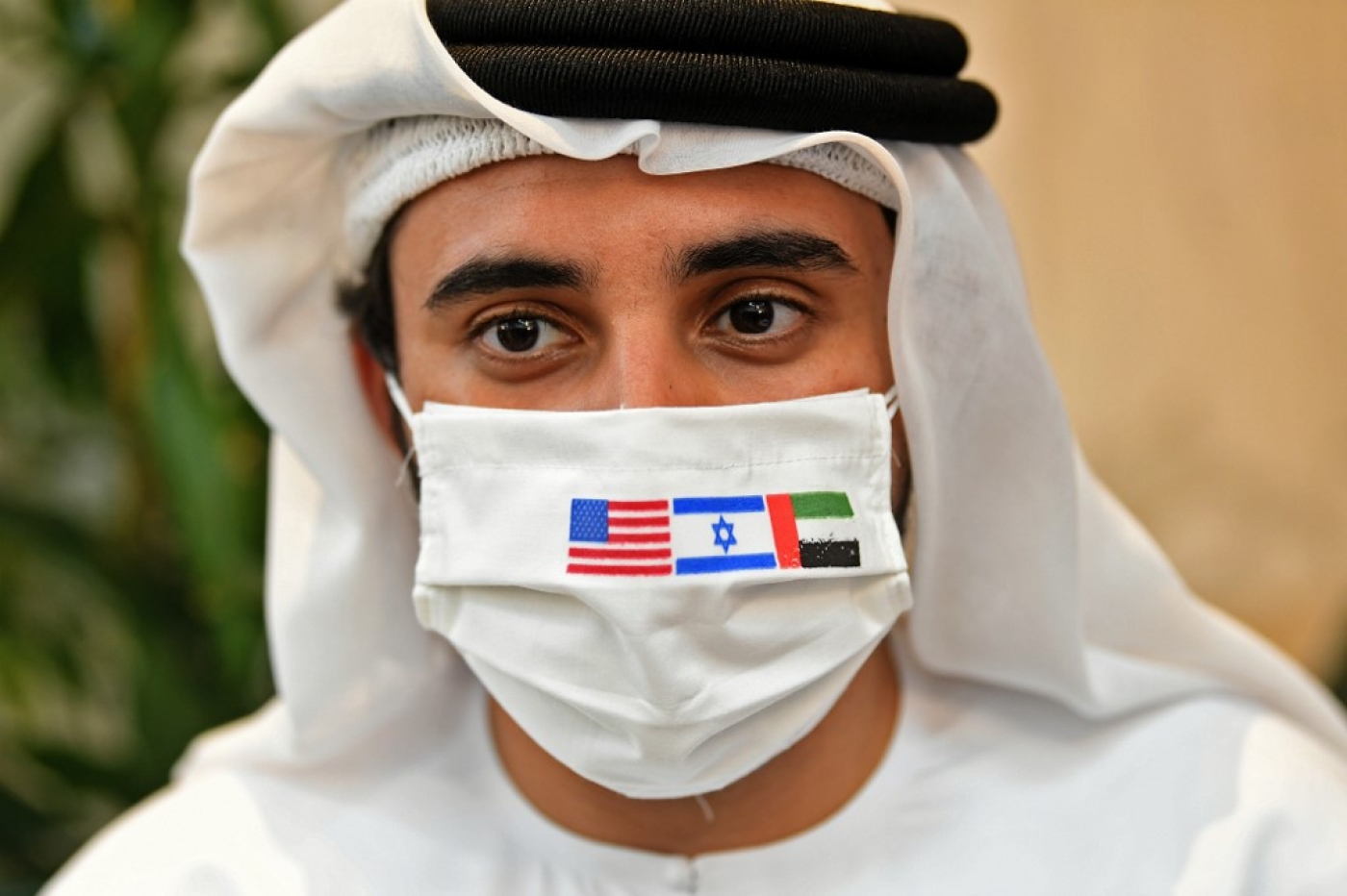 Une photo prise le 31 août 2020 montre un Émirati portant un masque de protection avec les drapeaux des États-Unis, d’Israël et des Émirats arabes unis avant l’arrivée du premier vol commercial en provenance d’Israël (AFP)