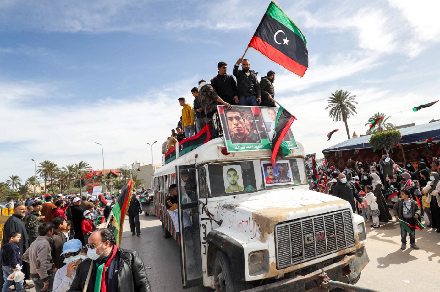 Les gens brandissent des drapeaux nationaux libyens dans la ville côtière de Tadjourah, à l’est de la capitale Tripoli, le 25 février 2022 (AFP/Mahmoud Turkia)