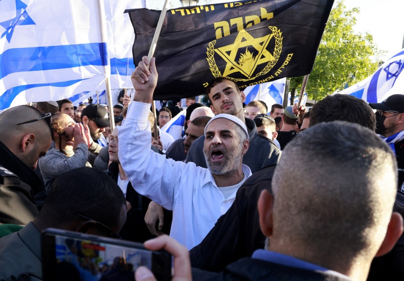 Israeli ultra-nationalists wave national and party flags during an unauthorised 'flags march' in Jerusalem on 20 April 2022. (AFP)