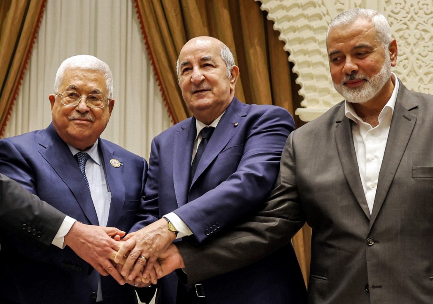 A handout picture provided by the Palestinian Authority's press office (PPO) on 5 July 2022 shows (L to R) Palestinian president Mahmud Abbas shaking hands with Algerian President Abdelmajid Tebboune and with Palestinian Hamas movement's leader Ismail Haniyeh. (AFP) 