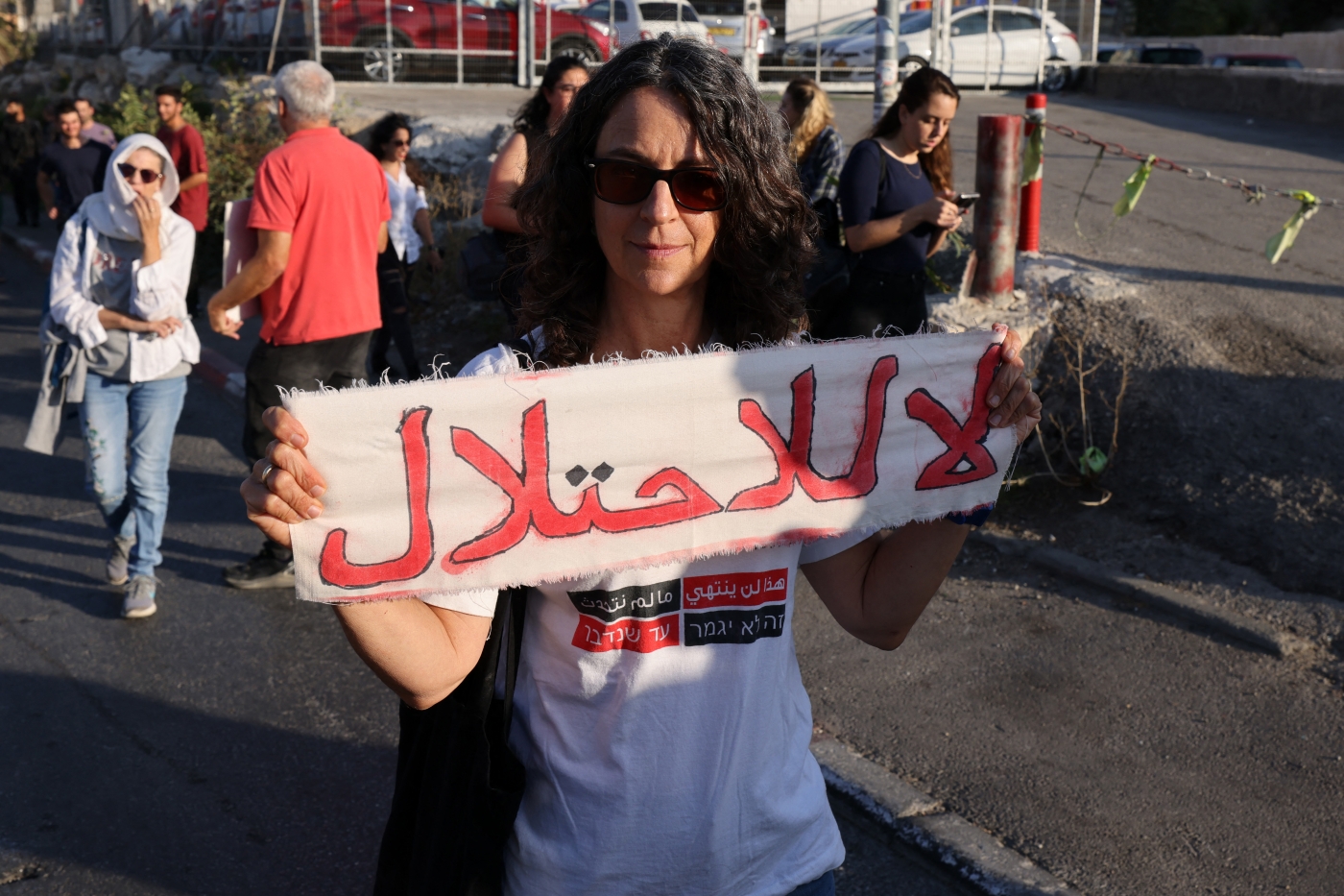 Une femme tient une banderole où est écrit « Non à l’occupation » lors d’un rassemblement organisé par des militants étrangers, palestiniens et israéliens dans le quartier de Sheikh Jarrah à Jérusalem-Est occupée, le 14 octobre 2022 (AFP)