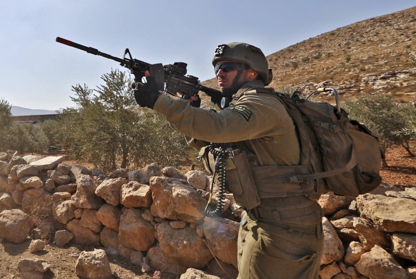 An Israeli soldier takes aim at Palestinians during a protest against the establishment of Israeli outposts, in Beit Dajan, east of the occupied West Bank city of Nablus, on 4 November 2022 (AFP)