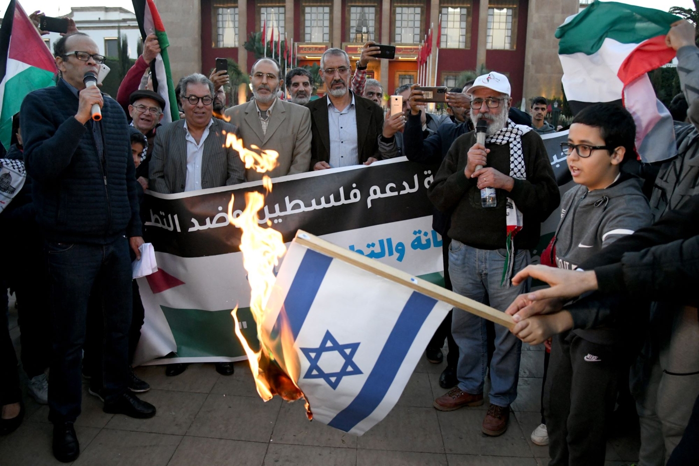 Moroccans burn the Israeli flag as they gather to protest the normalisation of ties with Israel, outside the parliament building in the capital Rabat on December 24, 2022 (AFP)