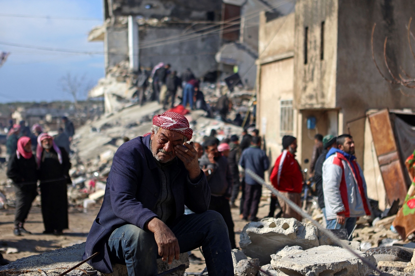 A Syrian man cries as he sits on the rubble of a collapsed building in the rebel-held town of Jindayris on 7 February 2023, following a deadly quake (AFP)