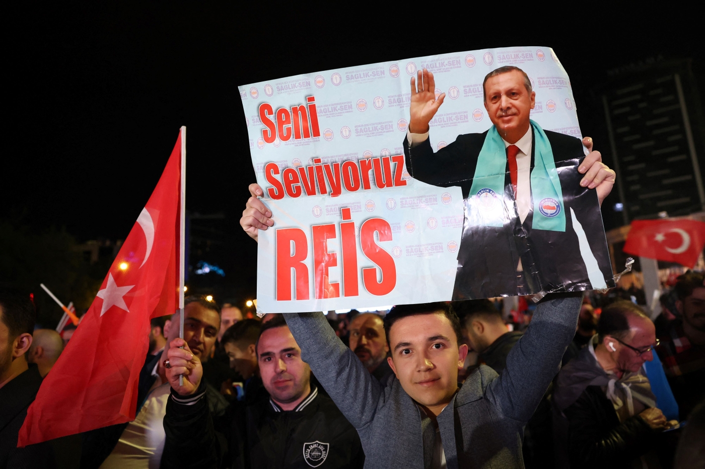 A supporter of Turkish President Tayyip Erdogan holds a poster which reads "We Love You Chief" outside the AKP headquarters after polls closed in Turkey's presidental and parliamentary elections in Ankara, Turkey May 15, 2023. Turkey is braced for its first election runoff after a night of high drama showed President Recep Tayyip Erdogan edging ahead of his rival but failing to secure a first-round win (AFP)