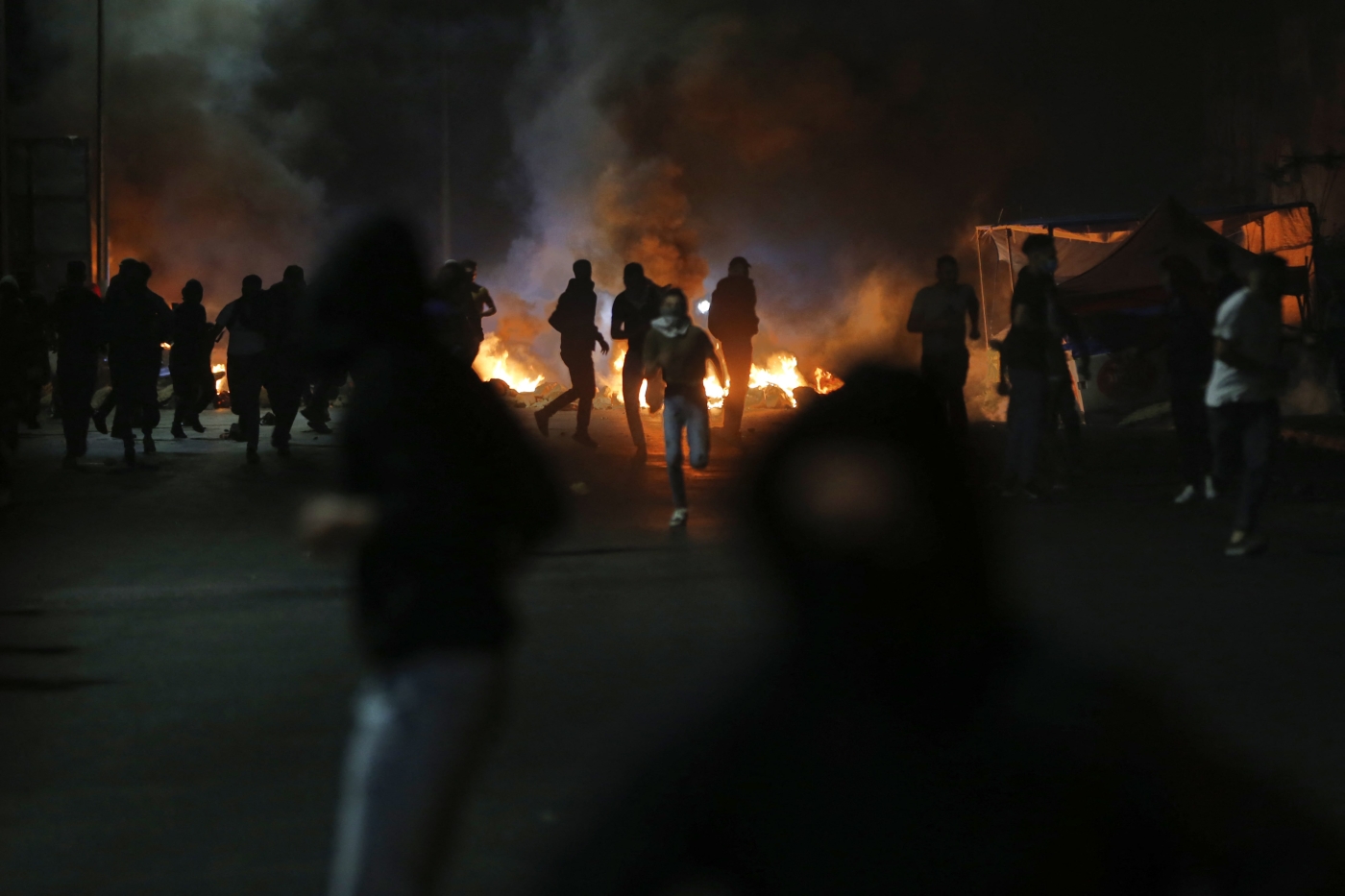 Palestinian demonstrators run away from gas
