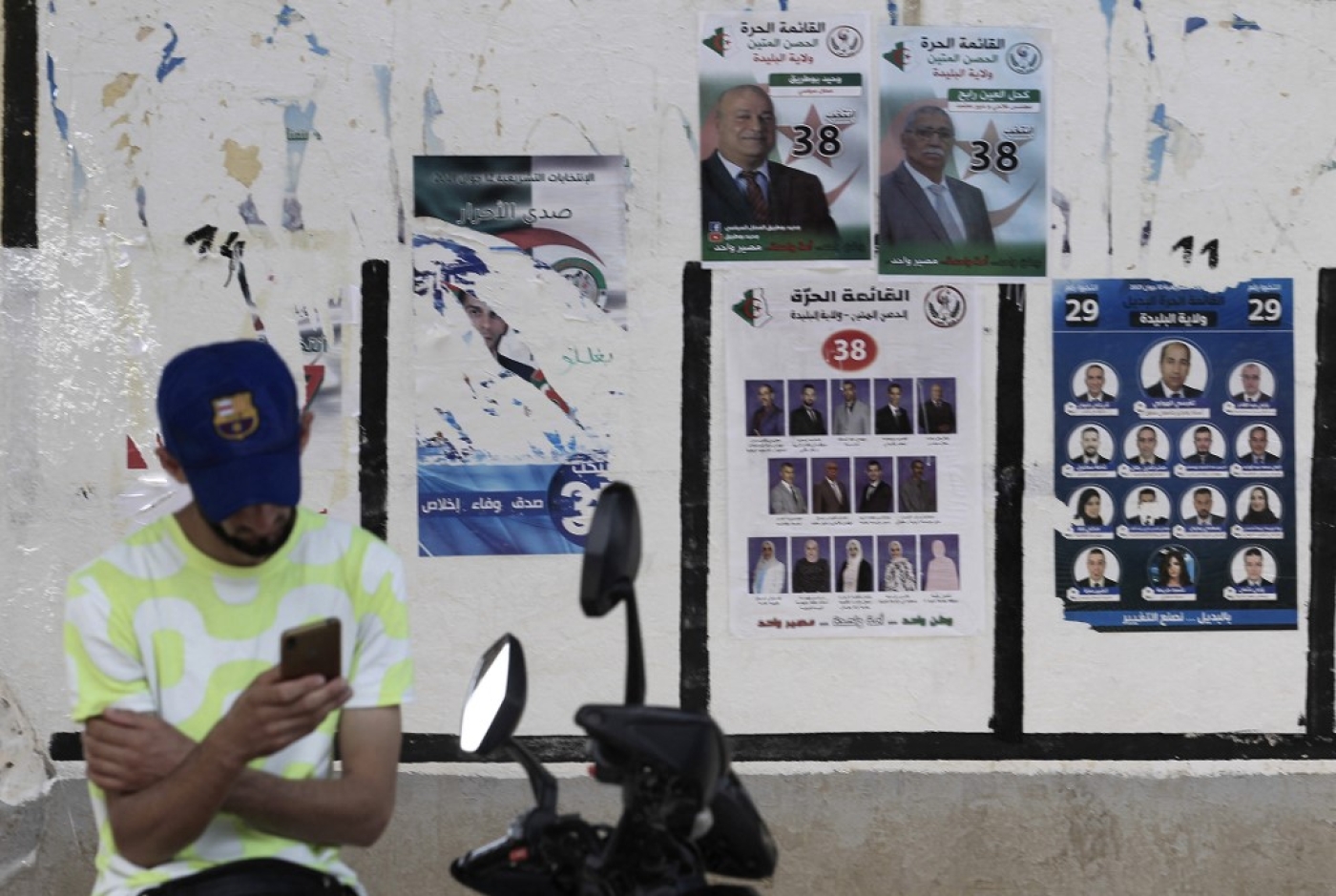 Un Algérien consulte son téléphone devant des panneaux électoraux, le 31 mai 2021 (AFP)