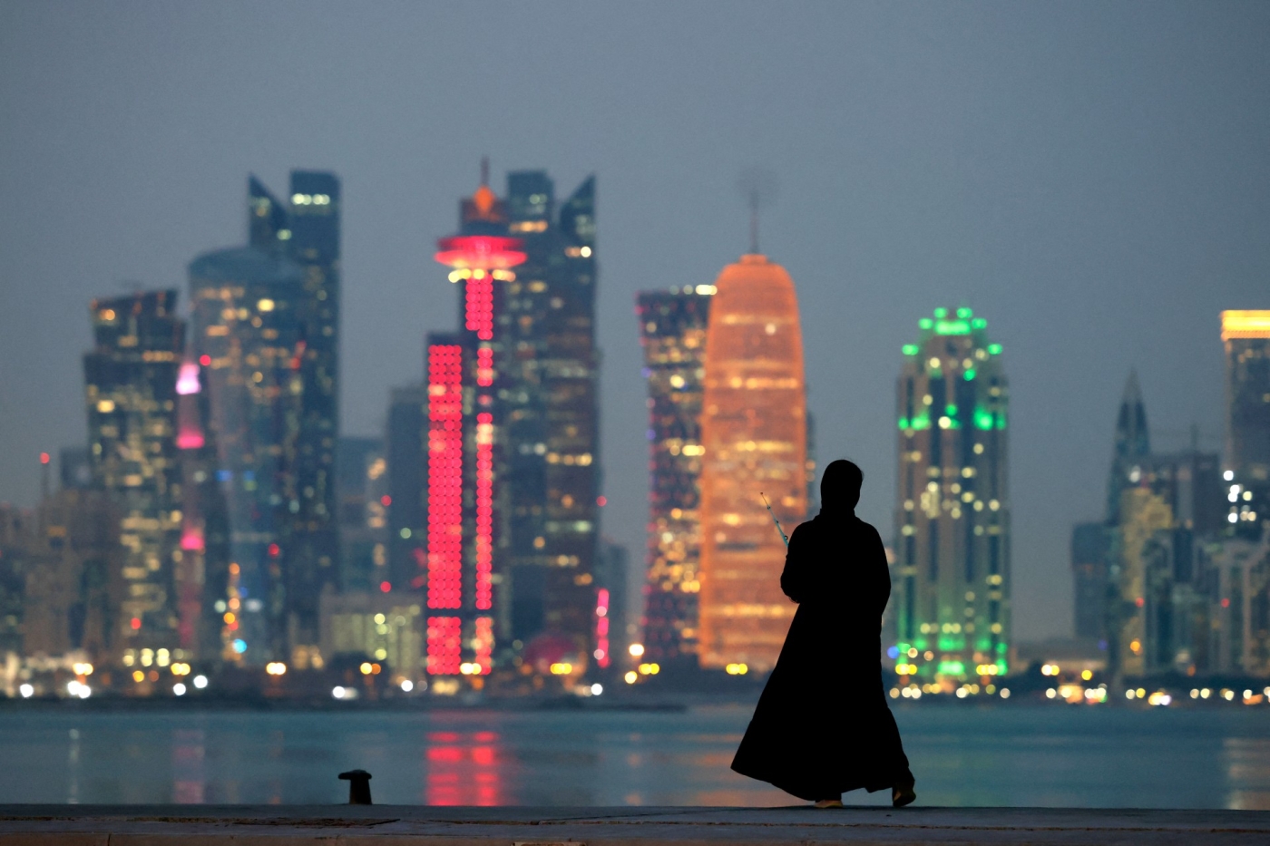 A woman stands by the waterfront overlooking the towered skyline of Qatar's capital Doha (AFP)