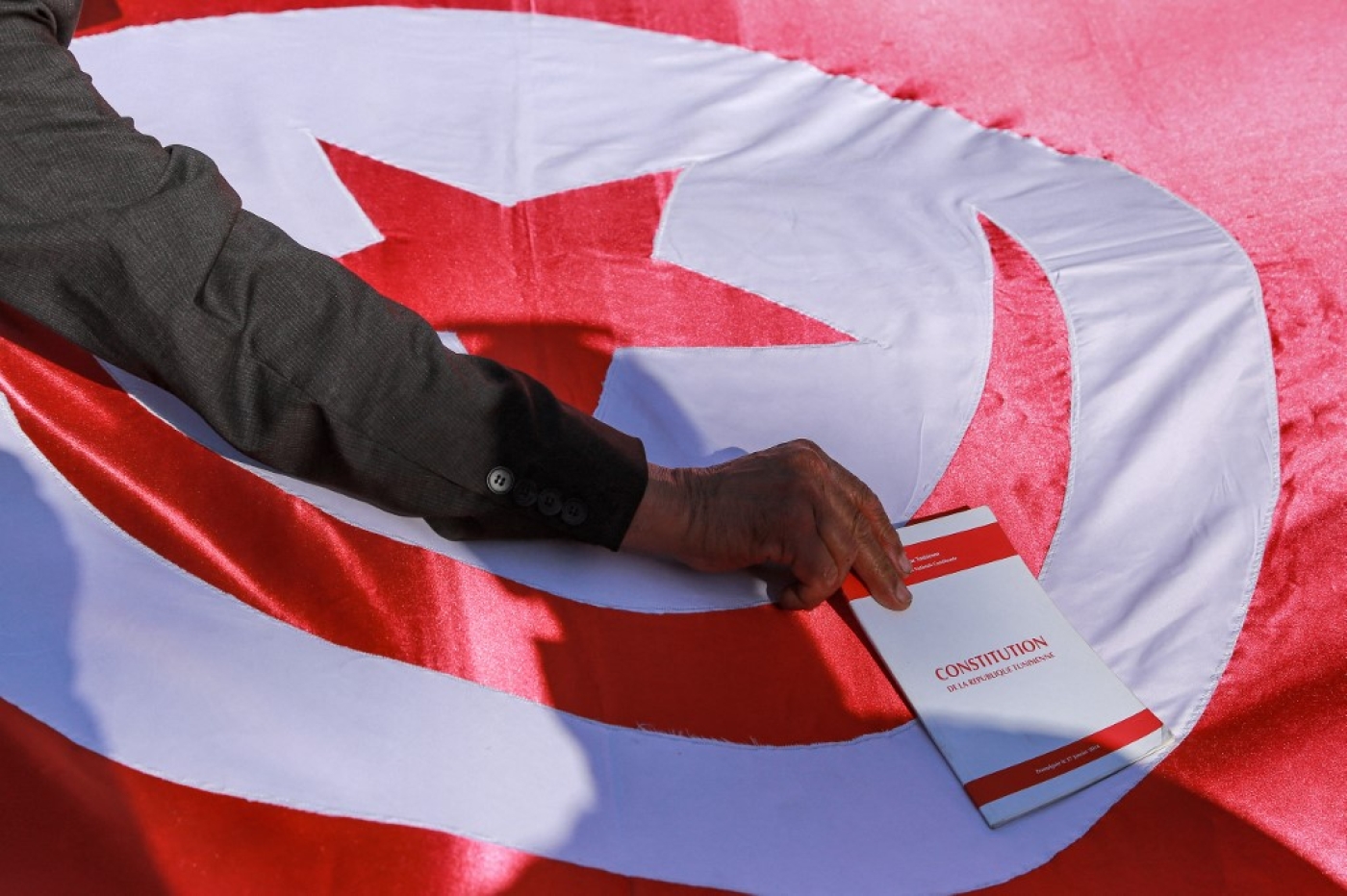 Un manifestant met une copie de la Constitution tunisienne sur un drapeau tunisien lors d’une manifestation à Tunis contre le président Kais Saied, le 23 février 2022 (AFP/Anis Mili)