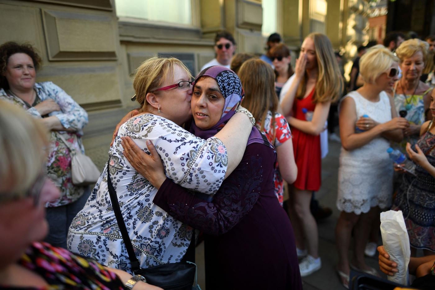 A Muslim woman who attends Didsbury Mosque hugs another lady as she are her family hand out biscuits to members of the public in central Manchester, northwest England on May 26, 2017, as a gesture of solidarity (AFP)