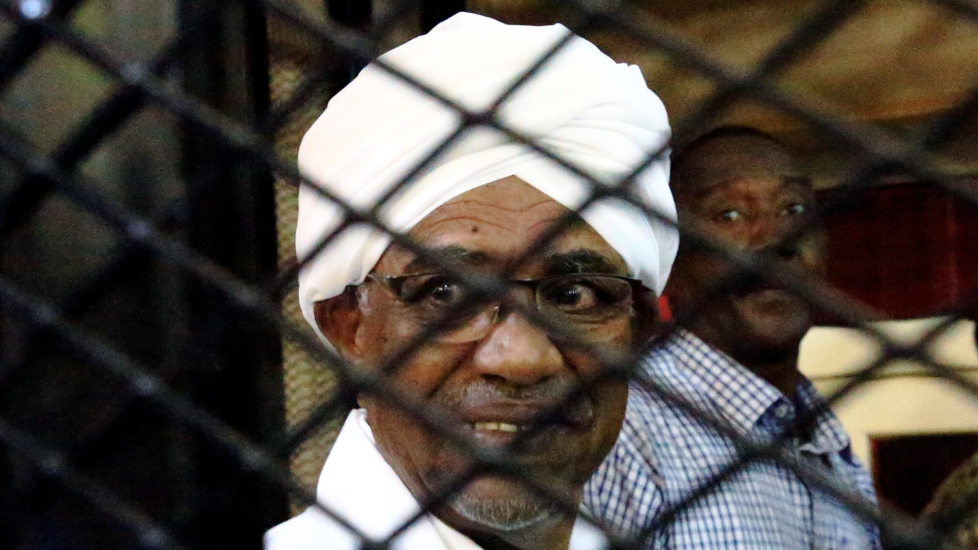 Sudan's former president Omar Hassan al-Bashir smiles as he is seen inside a cage at a courthouse in Khartoum in 2019 (Reuters)
