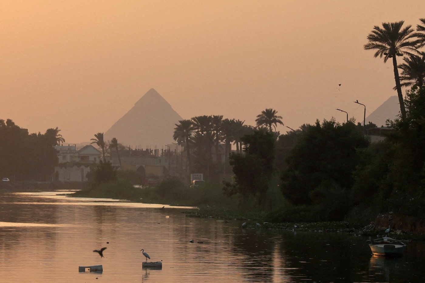 The Pyramid of Khufu seen before sunset behind a canal which flows into the River Nile on the outskirts of Cairo on 4 August 2022 (Reuters)