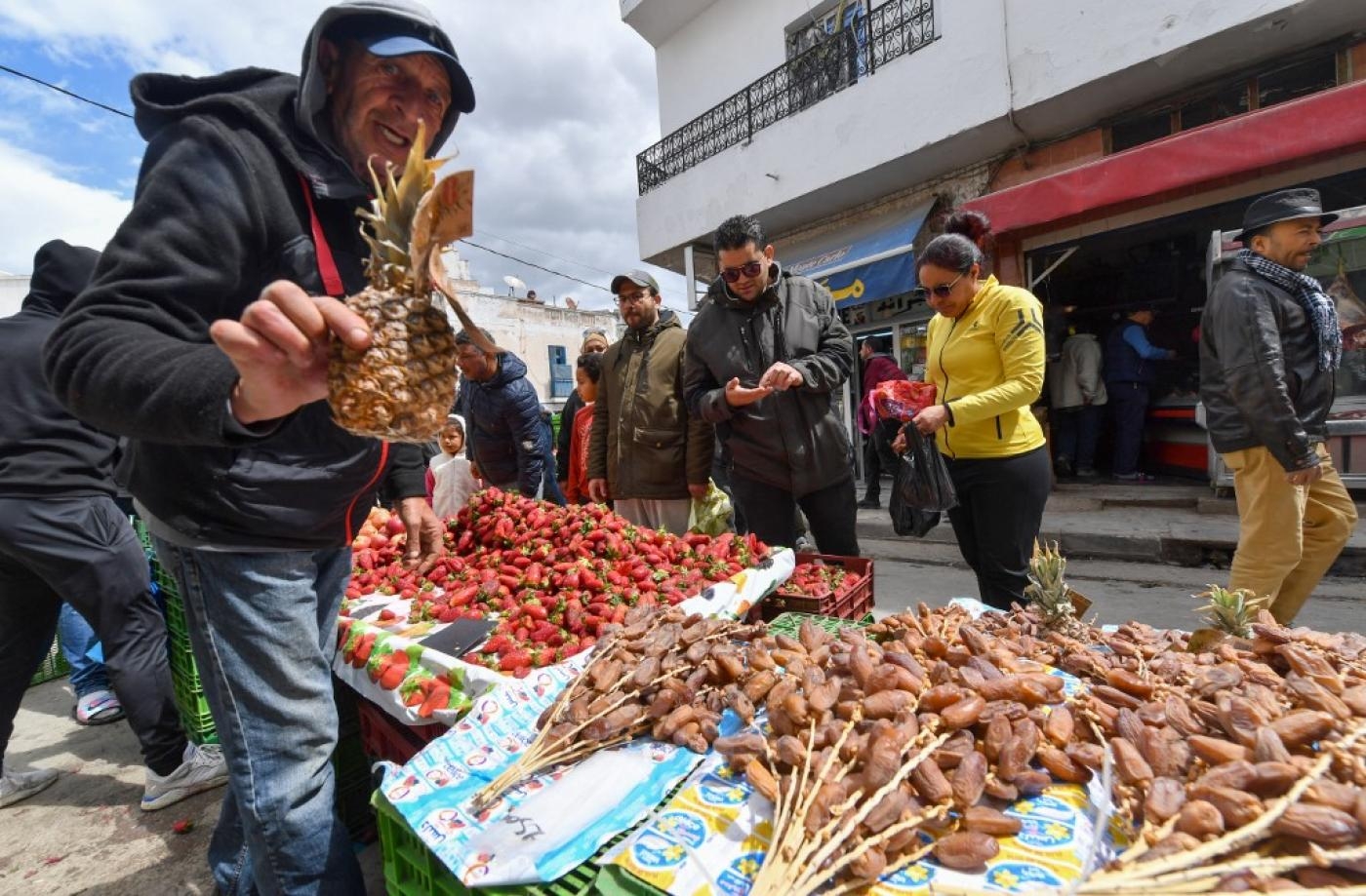 Un vendeur de rue présente un ananas sur un marché de L’Ariana, près de la capitale Tunis, le 2 avril 2022 (AFP)