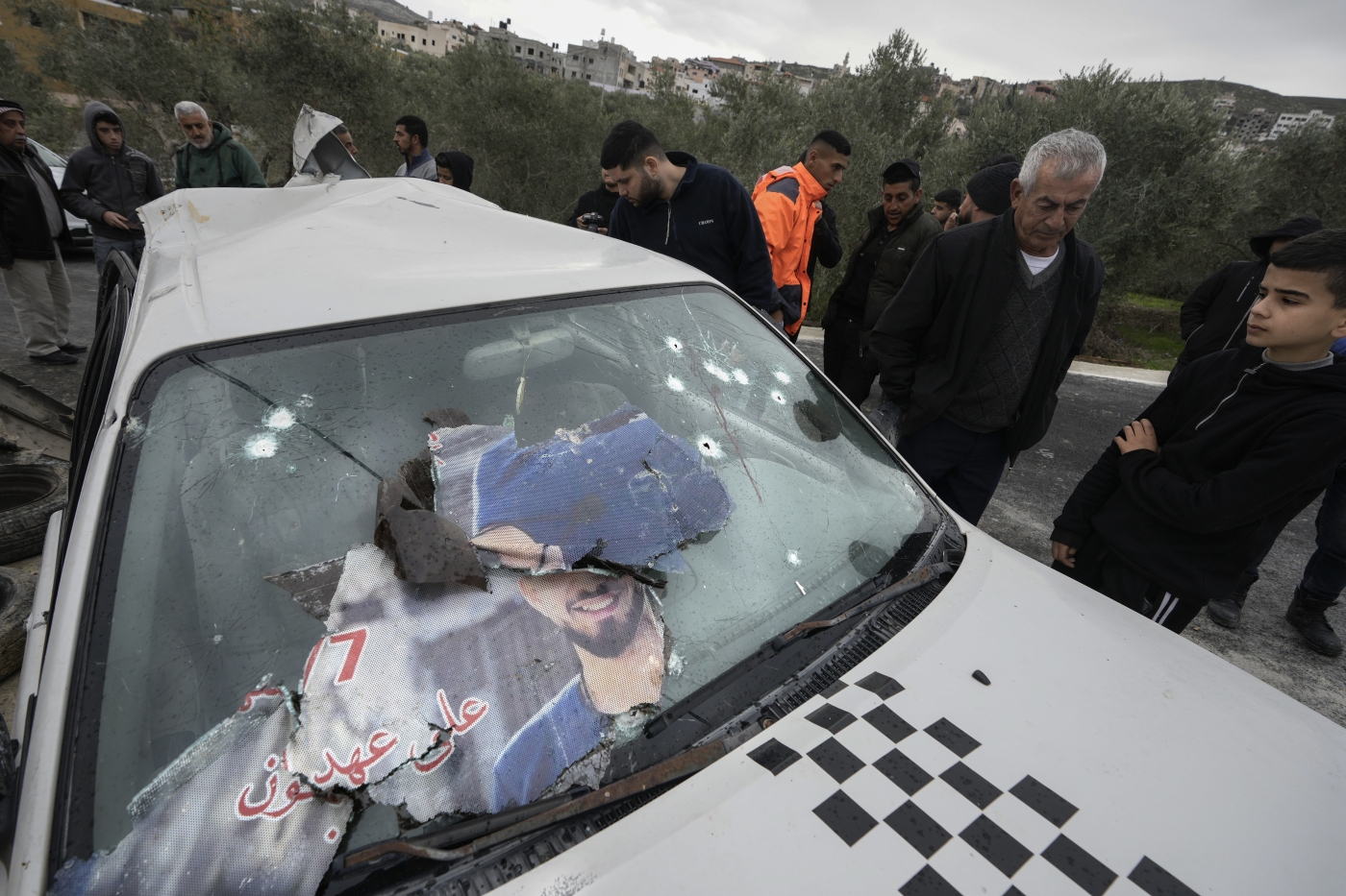 Palestinians inspect a car in which two men were shot dead by Israeli forces in the occupied West Bank village of Jaba on 14 January 2023 (AP)