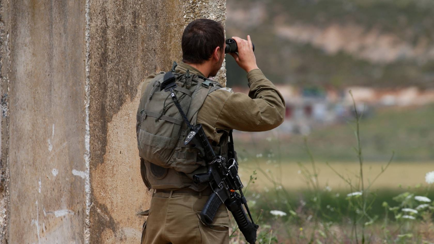 An Israeli soldier positioned near the northern town of Metula monitors the fence with Lebanon, 21 May 2022 (AFP)