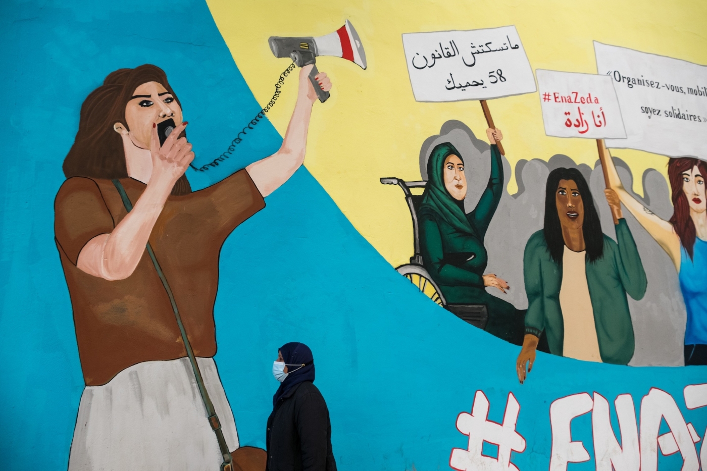 Une Tunisienne passe devant une peinture murale réalisée par l’ONG Aswat Nissa, dans le centre de Tunis, en janvier 2021 (MEE/Constantin Gouvy)