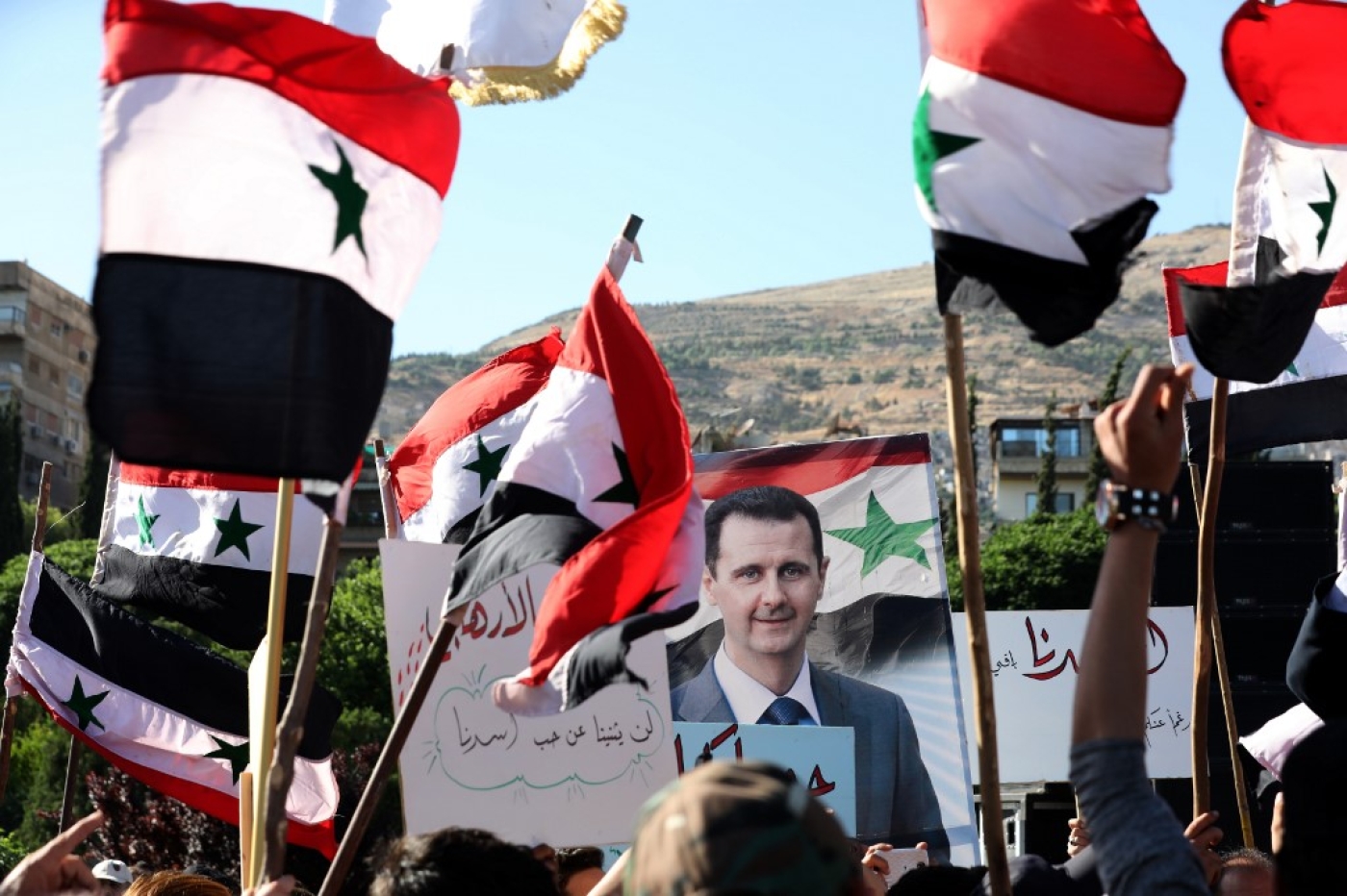 People wave Syrian national flags and pictures of President Bashar al-Assad
