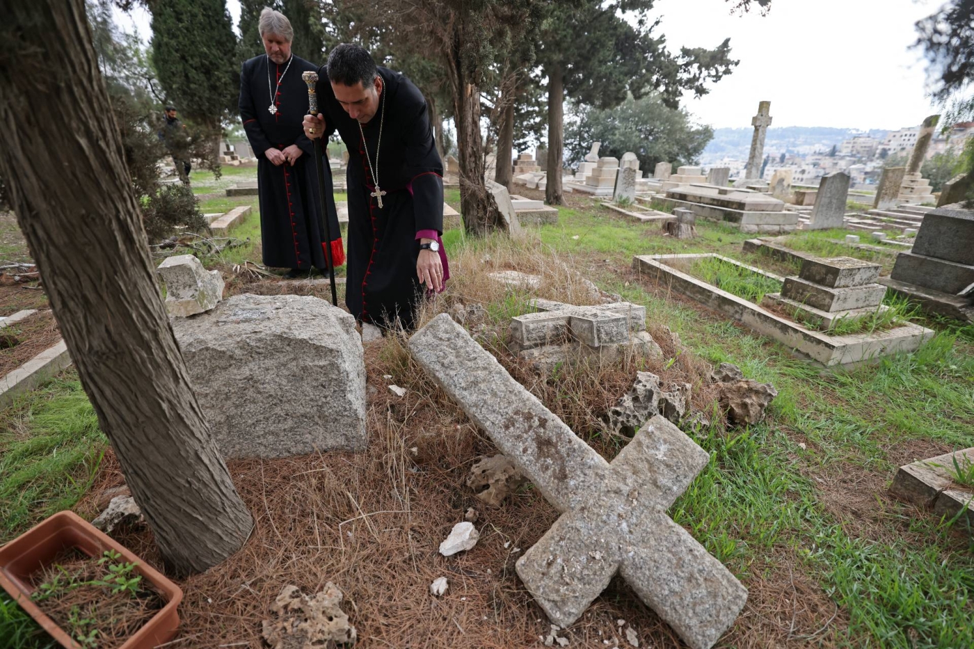 Hosam Naoum, archbishop and caretaker of the Protestant cemetery, inspects vandalised graves on Mount Zion outside Jerusalem's Old City, 4  January 2023 (AFP) 
