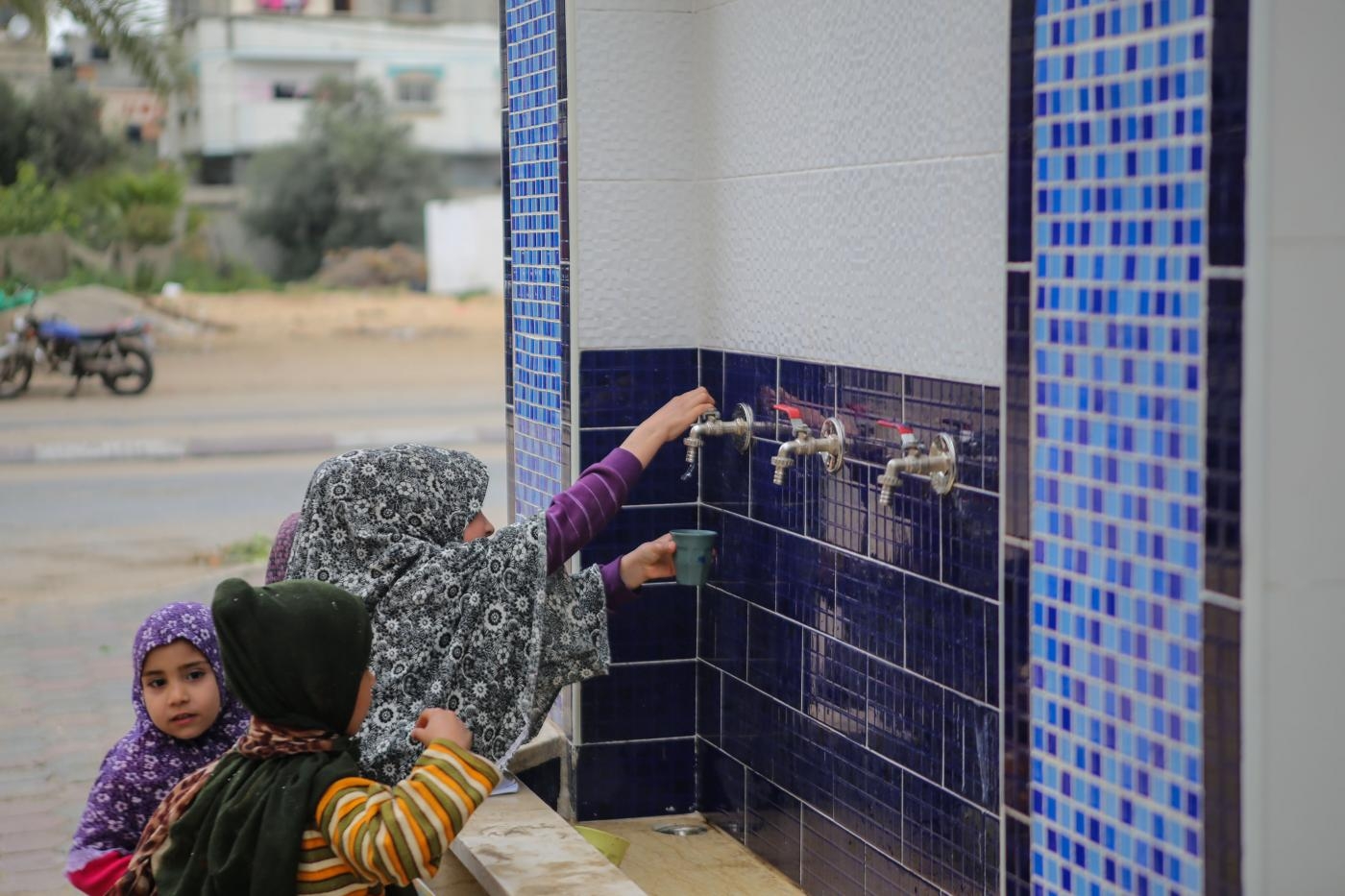 Des enfants palestiniens boivent de l’eau d’un réservoir public dans le camp de réfugiés d’al-Nuseirat à Gaza, le 15 mars 2019 (MEE/Mohammed al-Hajjar)