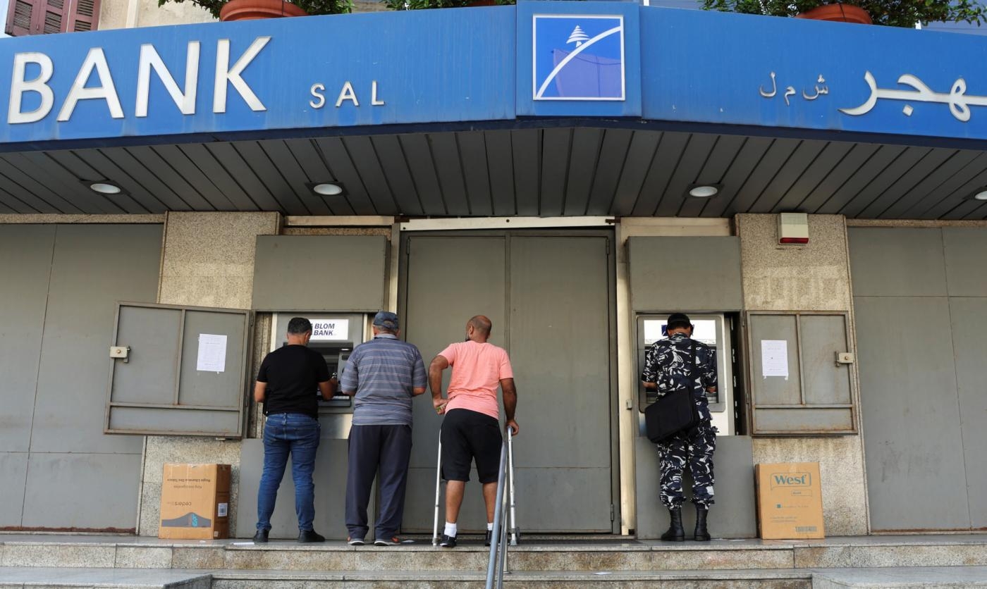 Des personnes utilisent les distributeurs automatiques d’une agence Blom Bank fermée, à Beyrouth, le 20 septembre 2022 (Reuters)