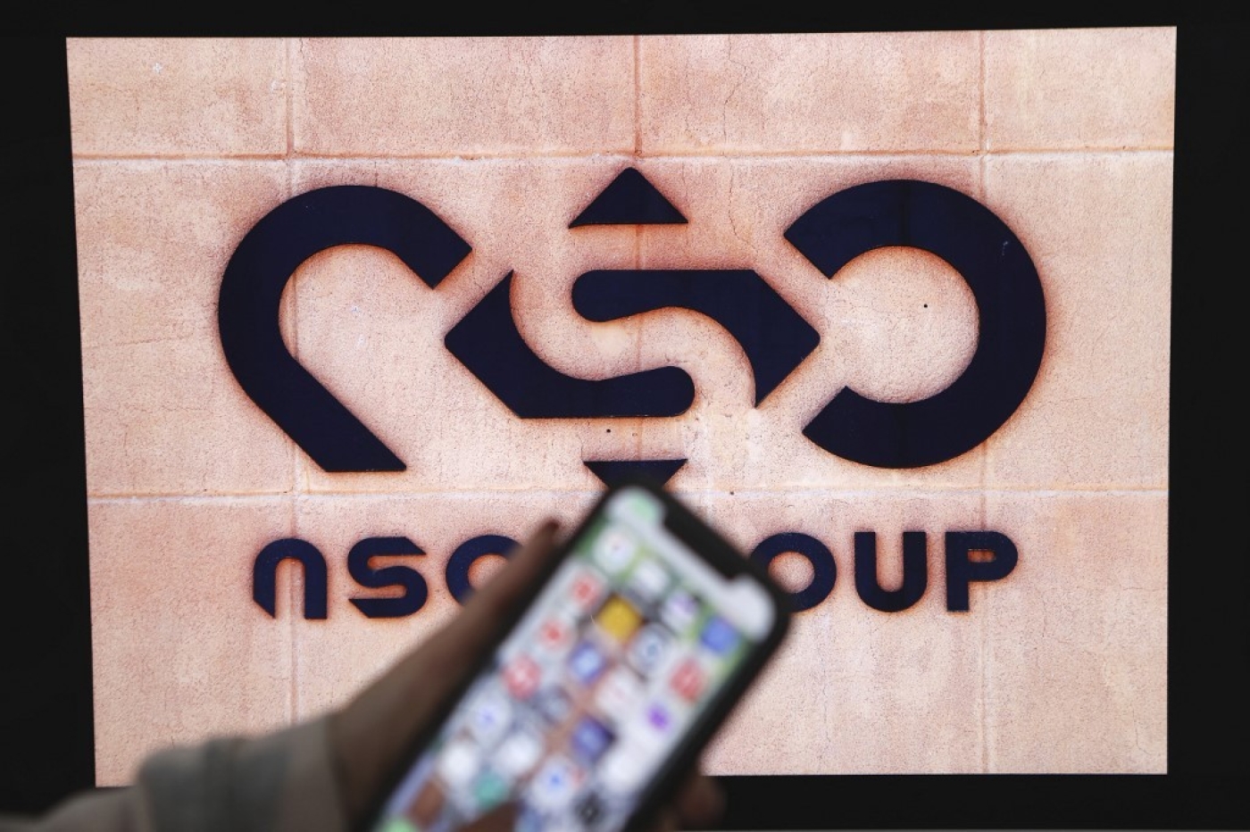 A photographic illustration shows a mobile phone near the NSO Group company logo in February 2022 in the Israeli city of Netanya (AFP)