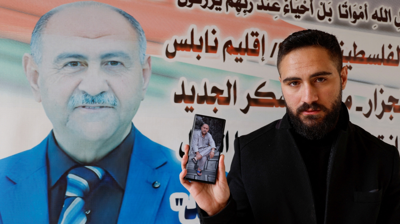 Palestinian nurse Elias al-Ashqar holds a picture of his father Abdel-Hadi, who was killed during an Israeli raid, in Nablus, in the occupied West Bank, 23 February 2023 (Reuters)