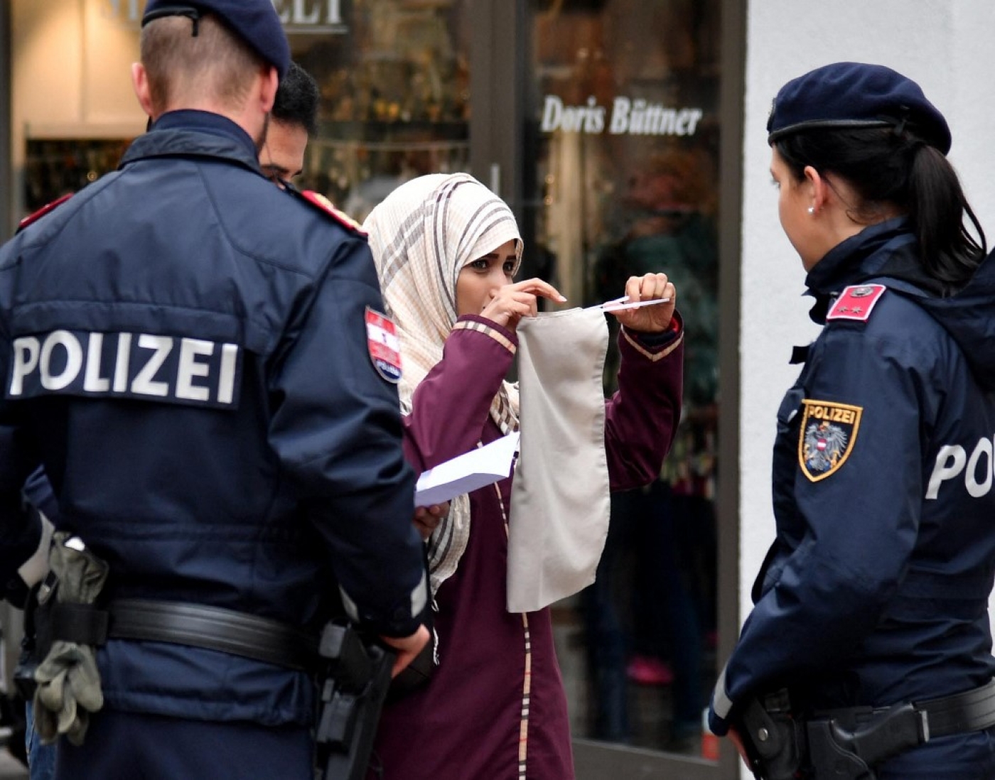 Police officers ask a woman to unveil her face in Zell am See, Austria, on 1 October 2017, following the country's ban on full-face Islamic veils coming into force (AFP)