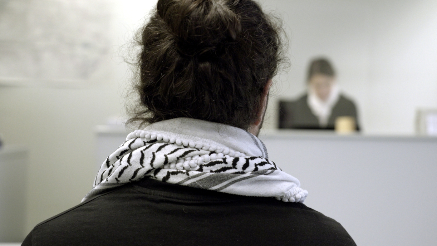 A defendant wearig a Palestinian kefiyyeh faces a judges in the courtroom in Berlin, 16 March 2023 (Tom Wills/MEE)