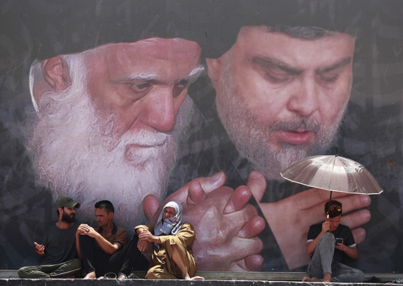 Supporters of Muqtada al-Sadr attend Friday prayers in Sadr City under a mural of the Shia cleric (portrait R), east of the Iraqi capital Baghdad on 17 June 2022 (AFP)