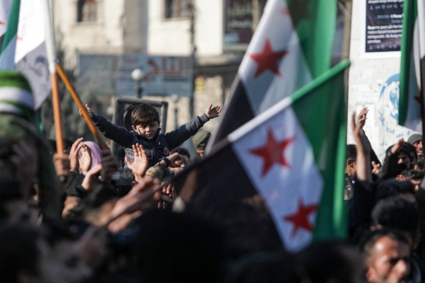 Demonstrators raise Syrian opposition flags and placards as they rally against a potential rapprochement between Ankara and the Syrian regime, on December 30, 2022, in the opposition-held city of al-Bab, on the border with Turkey (AFP)