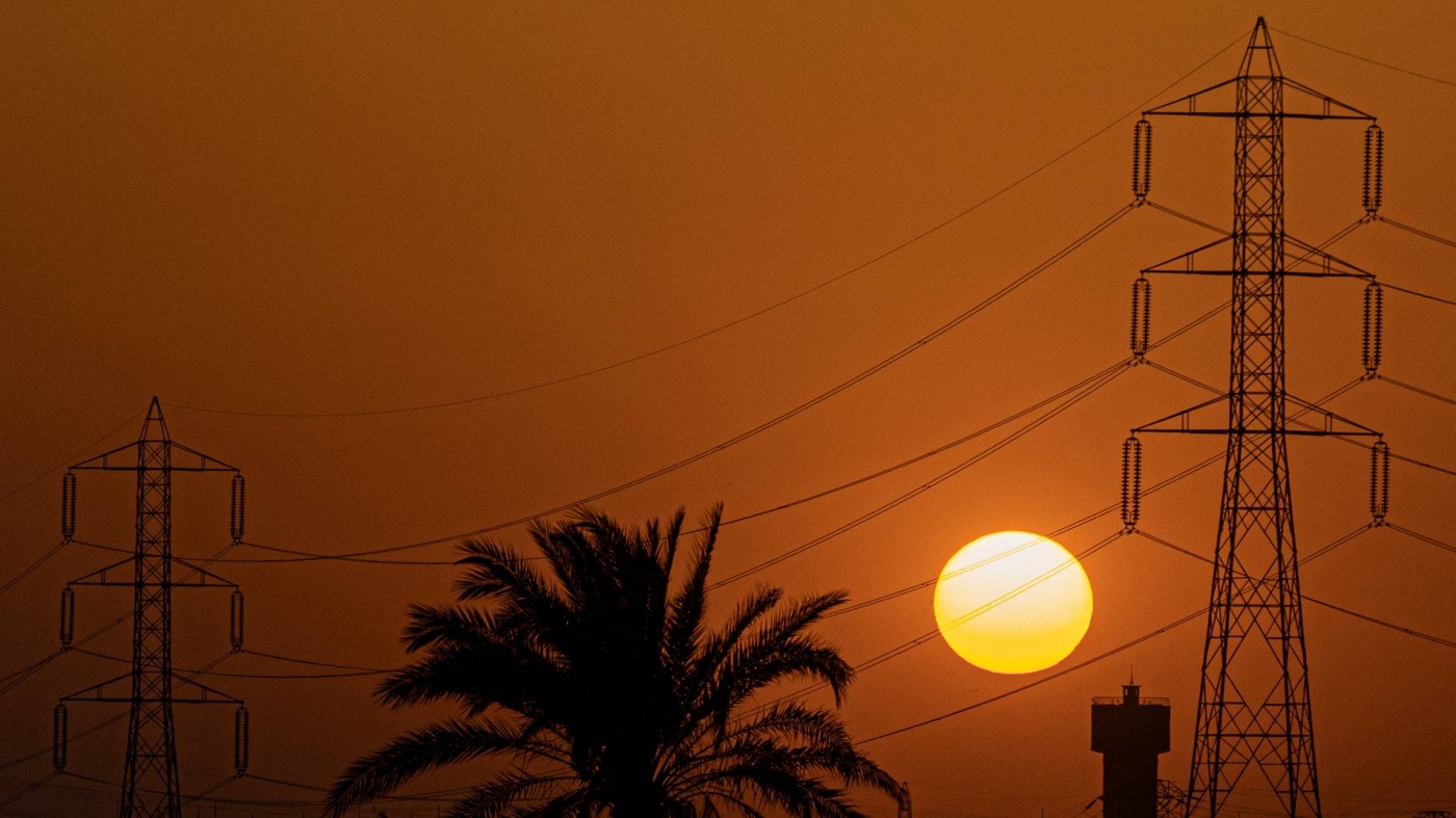 The sun sets behind high voltage transmission towers in Egypt's Qalyubia governorate of the Nile Delta, 26 June 2022 (AFP)